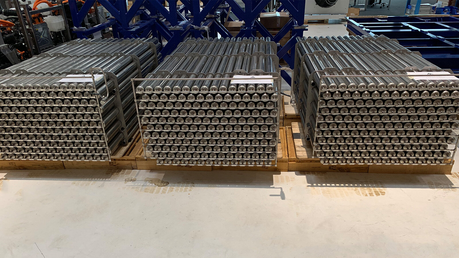 Drei nebeneinander liegende Wasserstoff-Feststoffspeicher, jeweils bestehend aus 154 Edelstahlrohren warten darauf in einen 20" Container eingebaut zu werden. Die Rohre sind etwas 2mm lang und haben einen Durchmesser von 60,3mm.  Alle Rohre sind über horizontal verlaufende Rohrleitung miteinander verbunden. Diese Querleitungen münden auf der linken Seite von jedem Rohrkubus in einem vertikal angeordneten Steigrohr.