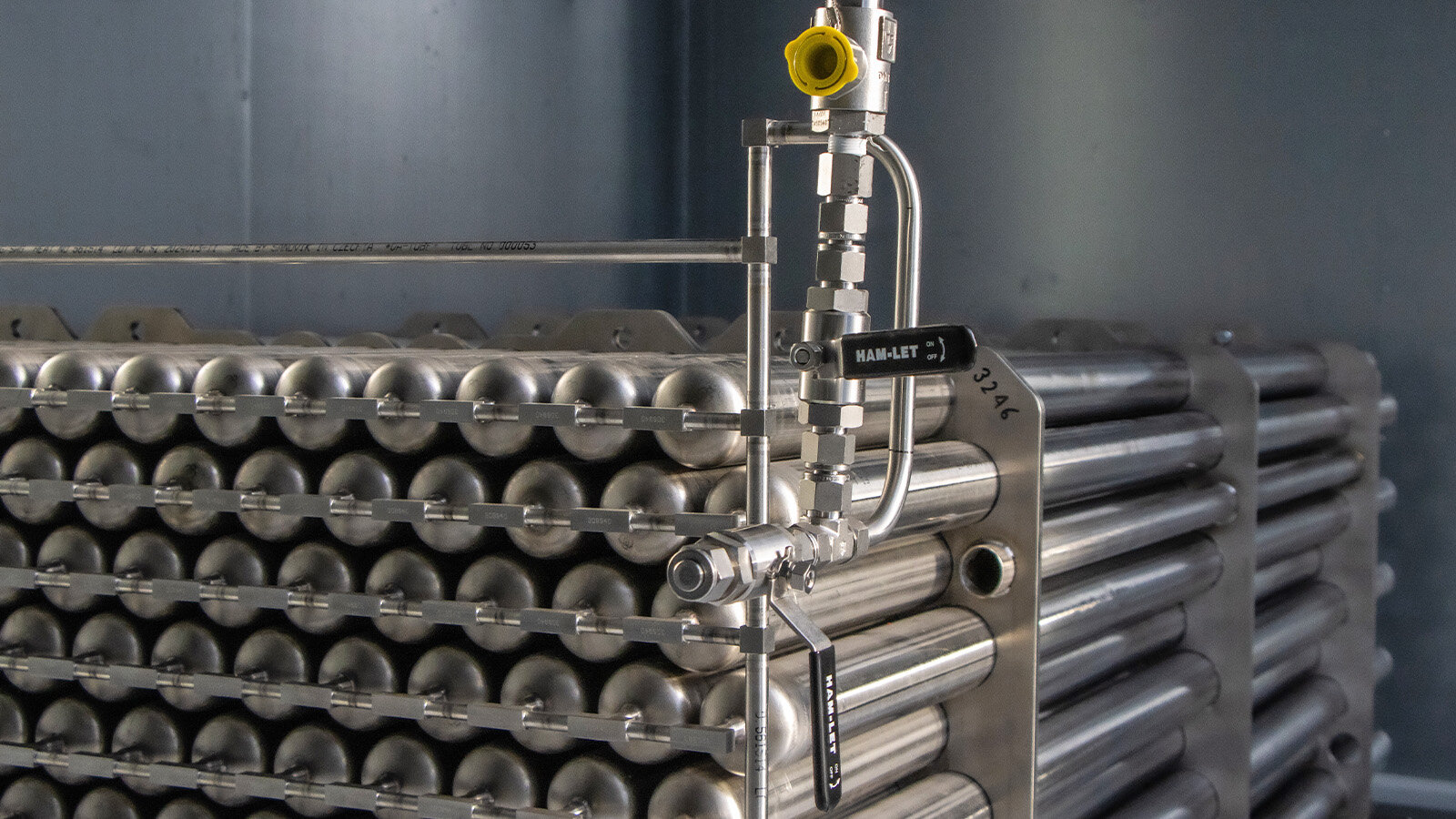 Dargestellt ist das Speichermodul bestehend aus mehreren Reihen von Edelstahlrohren. Die Rohre haben einen Durchmesser von 60,3 mm und einen Länge 930mm. Alle  Edelstahlrohre sind an der Stirnseite mit quer verlaufenden kleinkalibrigen Rohren mit Schweißverbindungen miteinander verbunden. Zusätzlich wird ein gelbes Ventil dargestellt und der Hintergrund ist schwarz. 